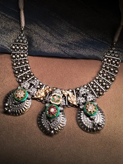 Mystic metals that carry the soul of tradition. This oxidized silver necklace features three large medallions with colorful enamel and polki work.
