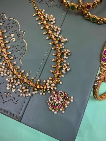 A beautiful Maharashtrian-style necklace with delicate pearl clusters and colored stones, paired with matching bangles. This set is perfect for a bride or for attending a wedding.