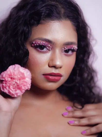 A close-up of a creative makeup look featuring pink eyeshadow adorned with delicate pearls. This artistic choice adds texture and a high-fashion element to the portrait.