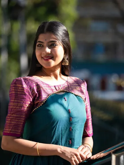 A close-up portrait in a teal gown with a contrasting purple yoke. The focus is on the delicate beadwork along the neckline and the rich colors of the outfit.
