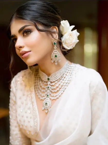 A close-up portrait showing how a soft, romantic updo with face-framing pieces can beautifully complement a modern bridal look with diamond jewellery.