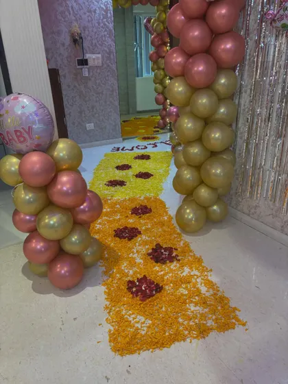 A closer look at the welcome home decor, showing the flower rangoli path flanked by pink and gold balloon pillars.