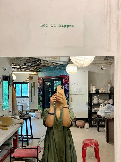 A mirror selfie in a pottery studio with the words "Let it happen." A reminder to embrace the creative process and allow things to unfold naturally.