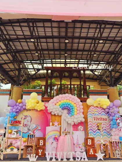 A vibrant unicorn and rainbow theme, perfect for a 5th birthday. The setup includes a large rainbow made of balloons, unicorn cutouts, and a pastel color scheme that brings this popular theme to life.