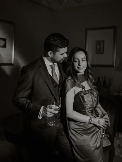 A quiet moment of connection during a reception. This black and white photograph focuses on the intimacy and elegance of the couple, away from the crowd.
