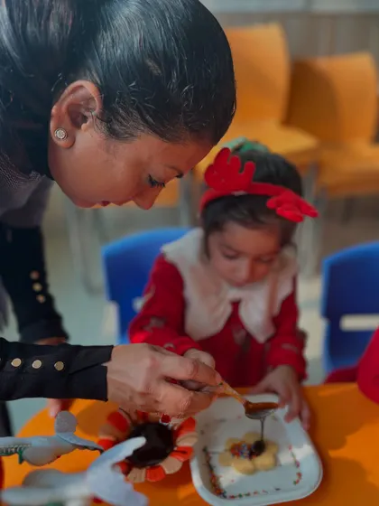 An instructor helps a child decorate a sweet treat, showing our hands-on guidance during workshops.