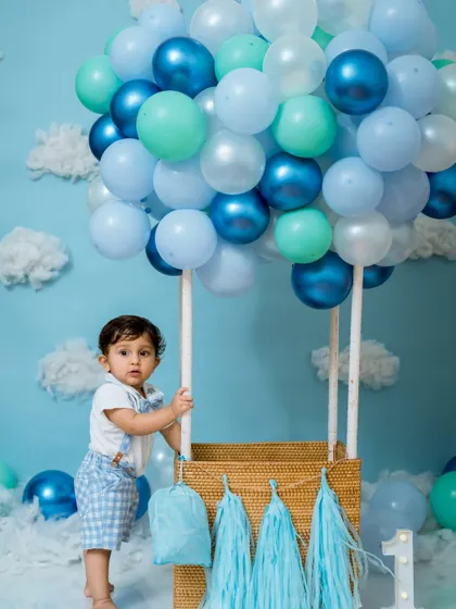 This little man is ready for his first birthday adventure in our hot air balloon. The shades of blue and fluffy clouds create a dreamy sky-high scene.