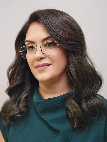 A portrait of our client rocking her new vibrant brunette color and layered cut, proving that glasses are a perfect style accessory.