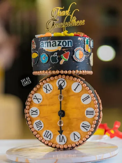 A client requested an anti-gravity cake for a 60th birthday with an antique clock as the showstopper. This was the result, a gravity-defying design where the clock face balances perfectly, surrounded by edible models of the husband's favorite brands and foods.