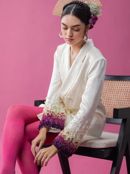 A full look from an avant-garde series, this image combines a sharply tailored blazer with bold, colorful tights. The contrast between the structured jacket and the vibrant legwear, along with the floral headpiece, creates a visually arresting, high-fashion statement.