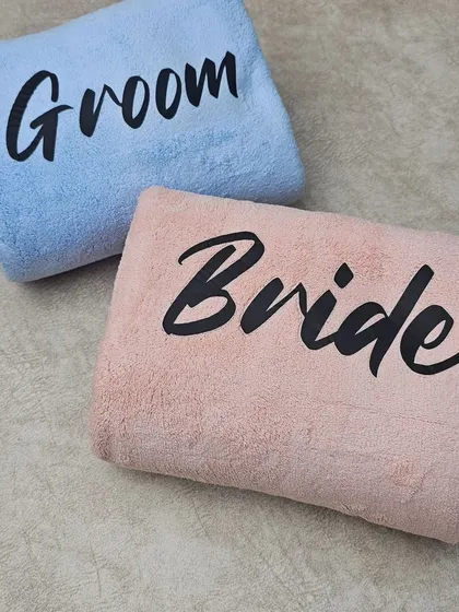 Another look at the folded 'Bride' and 'Groom' towels. The bold, modern font stands out beautifully against the pastel-colored fabric.