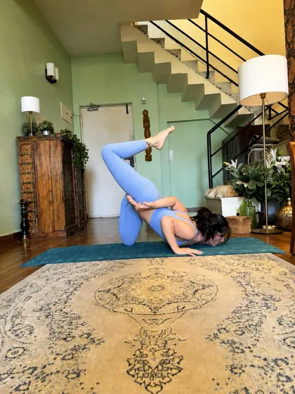 A crow pose variation on the living room rug, knees hugging the upper arms.