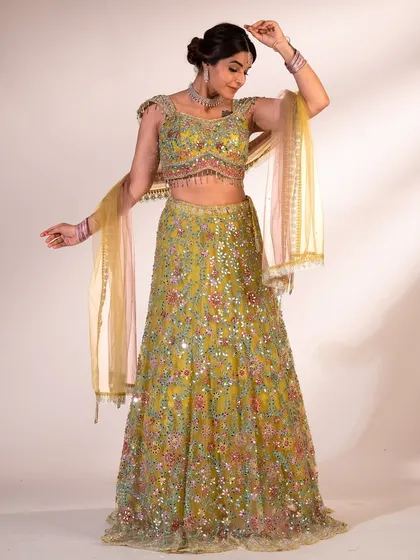 This lime green lehenga is a burst of joy. The multi-colored floral embroidery and sequin work create a vibrant, festive look that's perfect for a wedding celebration.