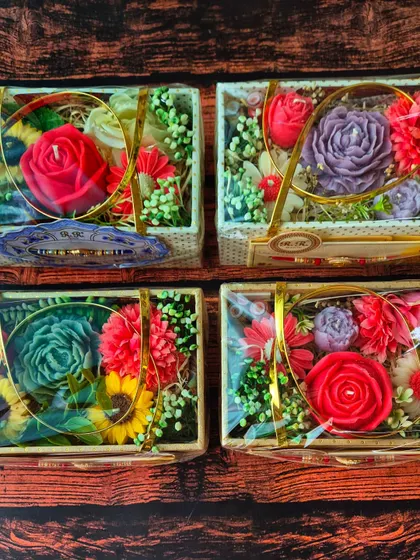 An overhead view of four different Flower Bouquet Gift Hampers, showing the variety of colors and flower candle shapes I can create.