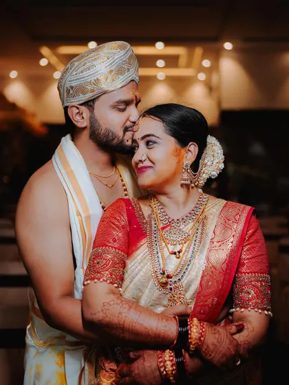 A warm and affectionate portrait of the couple, the groom kissing the bride's forehead.