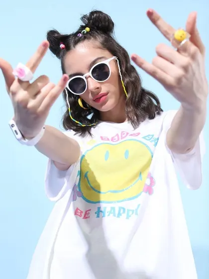 A "Be Happy" themed oversized tee styled with fun, chunky rings and white sunglasses for a bold and expressive look.