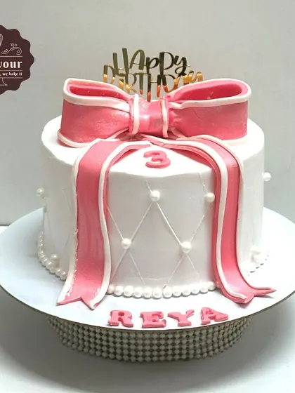 A beautiful gift-wrapped cake with a large pink bow and quilted pattern on the side. This design is a great example of how I use whipped cream and minimal fondant to create elegant textures.