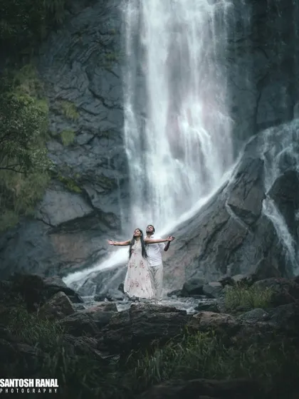 A majestic shot of a couple standing before a powerful waterfall. We seek out dramatic natural landscapes around Bangalore to create truly epic pre-wedding photographs.