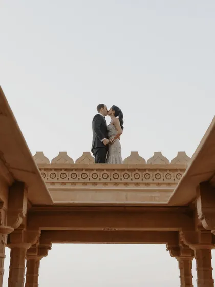 A kiss atop the ramparts of Suryagarh, Jaisalmer. The symmetrical architecture frames this epic, romantic moment against the sky, creating a powerful and memorable pre-wedding photograph.