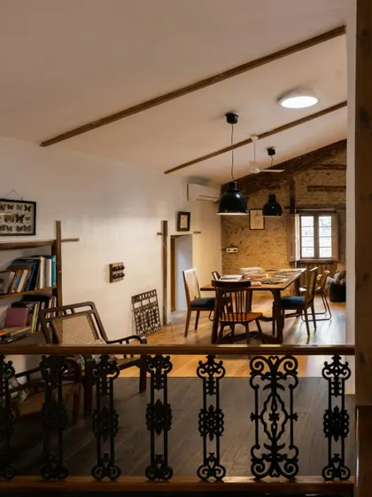 A view from the mezzanine in our studio, looking down at the main work area. You can see the restored wooden beams and the original wrought iron railing, details that we fought to preserve. The space feels open and collaborative, just as we intended.