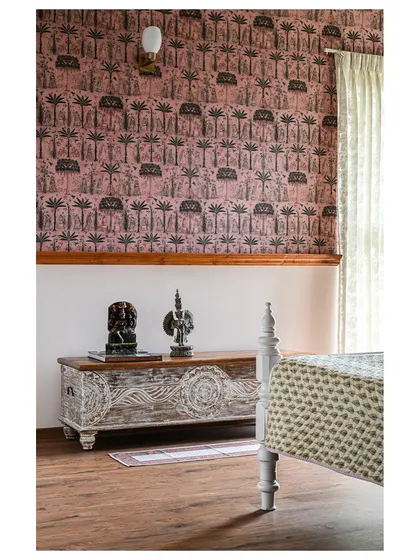We reused this heirloom teak wood bed, painting it white to work with the new decor. The carved chest and Sabyasachi wallpaper make it an inviting guest room.