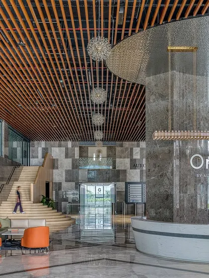 The grand, double-height lobby of the Aurobindo Orbit commercial building in Hyderabad. We used a rich palette of marble and wood, with a custom-designed metal jali screen, to create a sense of arrival that blends commercial sophistication with regional context. The space is designed to feel both impressive and welcoming, setting a new standard for corporate interiors.