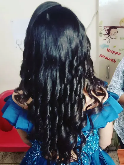 A back view of long hair styled into tight, defined curls, perfect for holding shape throughout a long event.