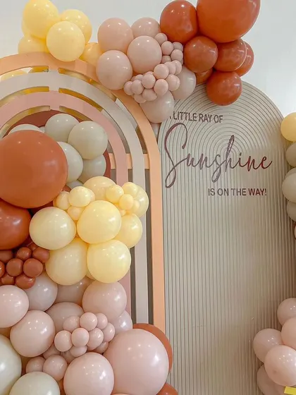A "Little Ray of Sunshine" is on the way. This baby shower theme uses warm, earthy tones and arched backdrops to create a joyful and welcoming atmosphere for the celebration.