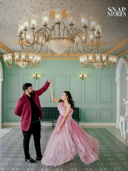 A playful dance under ornate chandeliers, capturing the couple's happiness in a grand, palace-like setting. This is a perfect example of a creative pre-wedding pose.