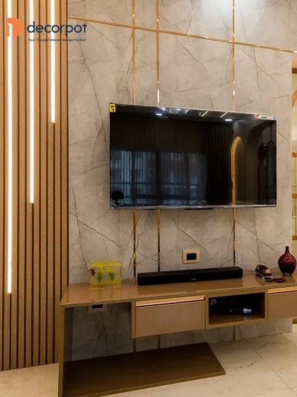 This design pairs a marble-finish wall with vertical fluted panels and integrated LED lighting. The floating console in a metallic finish adds to the modern, high-end aesthetic of the space.