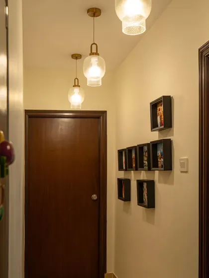 The renovated hallway in 'Blue Elegance' with new pendant lights and a gallery of family photos.