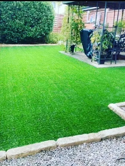 A simple, clean artificial lawn for a residential backyard. I edged it with stone pavers to create a neat border between the grass and garden beds.
