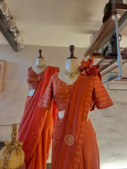 A complete look featuring the striped orange saree and detailed blouse. Paired with a statement necklace and a traditional potli bag, this ensemble is ready for any festive celebration.
