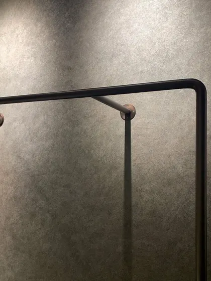 A detail of a custom metal railing. The clean lines, the subtle curve, and the contrast between the dark metal and the textured wall behind it showcase a distilled beauty that energizes the space.