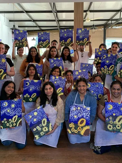 A group of happy painters showing off their Starry Night-inspired masterpieces. Our guided workshops make it easy for anyone to create a famous painting.