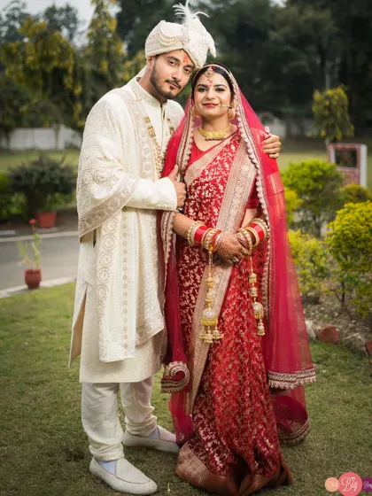 A classic portrait of the newlyweds, Aditya and Aditi, in their stunning red and white wedding attire.