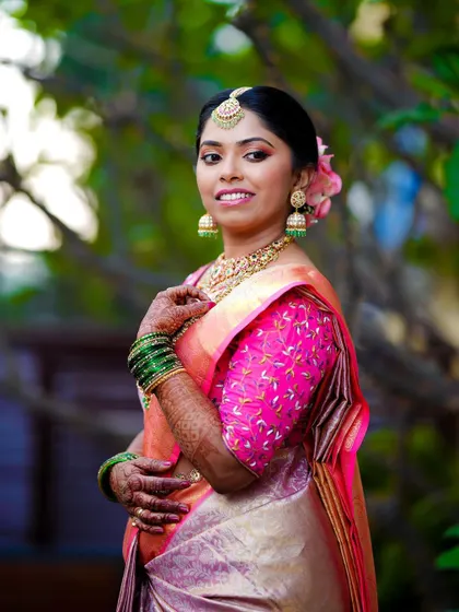 A beautiful portrait of the bride in a pink and gold saree, her smile radiating happiness.