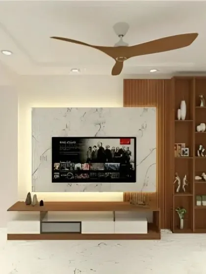 A modern TV unit featuring a white marble-effect backdrop with subtle backlighting. The console combines white and wood finishes, and is paired with a vertical wooden shelving unit for a balanced, asymmetrical look.