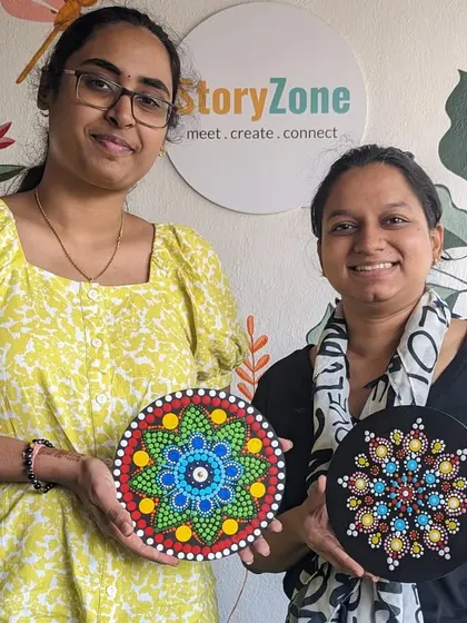 Two friends proudly displaying their finished dot mandalas. It's a great activity to do together, resulting in beautiful, personalized art.