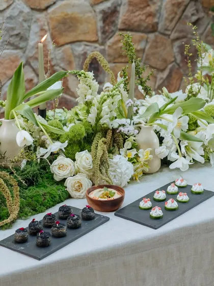 Savory bites are presented on modern slate trays, contrasting with the organic, flowing centerpiece of the Earth Table. This shows our blend of contemporary style and natural beauty.