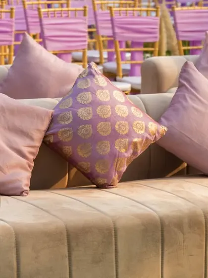 A close-up of the comfortable lounge sofas, featuring a mix of plain and patterned brocade cushions in shades of pink and gold that match the event's royal theme.