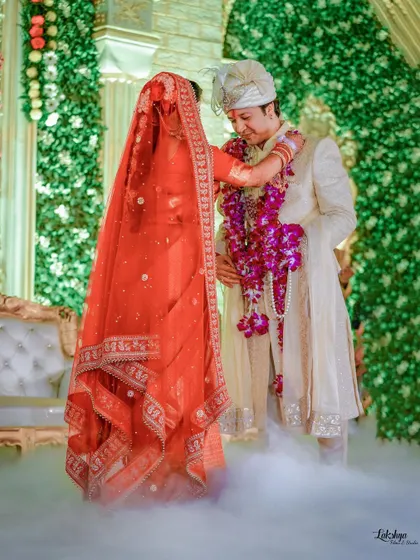 The Varmala ceremony, one of the most awaited moments. This shot captures the bride placing the garland on the groom, surrounded by a beautiful smoky effect.