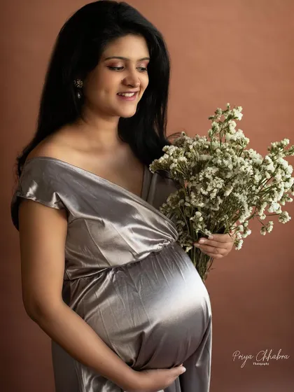 A glowing mama holding a bouquet of baby's breath. The metallic sheen of the dress and the delicate flowers create a beautiful contrast of textures.
