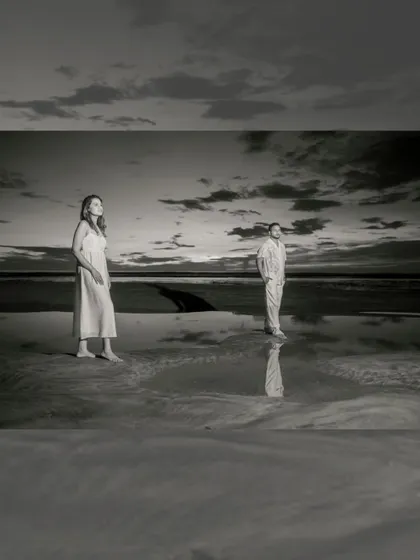 A dramatic black and white shot as dusk settles on the beach. The reflections in the wet sand and the moody sky create a powerful, artistic image.
