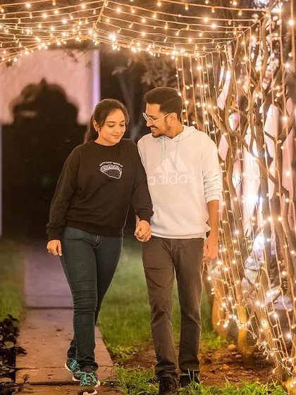 A lovely shot of a couple taking a romantic stroll through a tunnel of fairy lights.