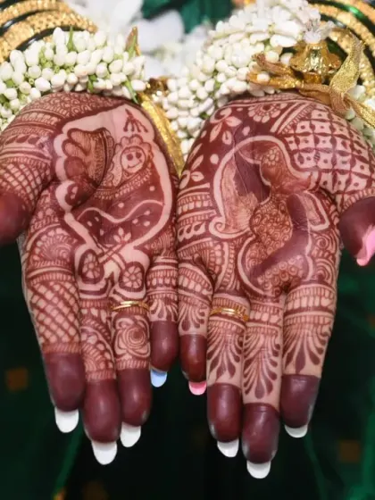 A detailed close-up of the intricate baby-themed mehndi on the mother's hands, a beautiful and symbolic part of the celebration.