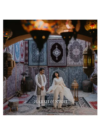 A beautifully composed shot of a couple in an ethnic-themed setting, surrounded by intricate carpets and lanterns. This image has a rich, cultural, and almost regal feel.