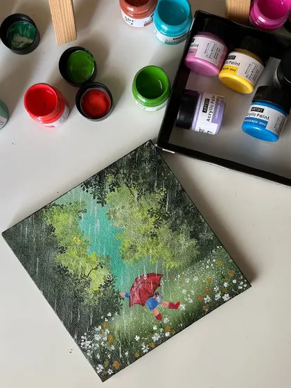 The rainy day painting from a top down perspective, surrounded by colorful acrylic paint pots.
