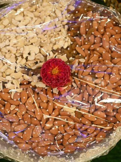 A beautifully arranged plate of dry fruits, with cashews and almonds separated and topped with a fresh flower. Simple, elegant, and healthy.
