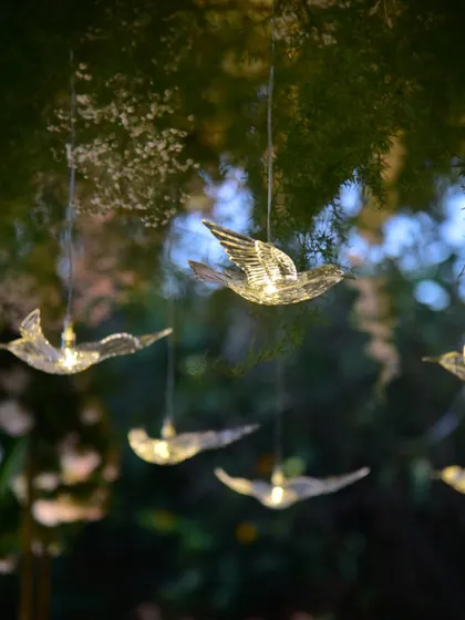 A close-up of the delicate, illuminated bird props we used for an outdoor wedding. These little details add a touch of magic to the decor.